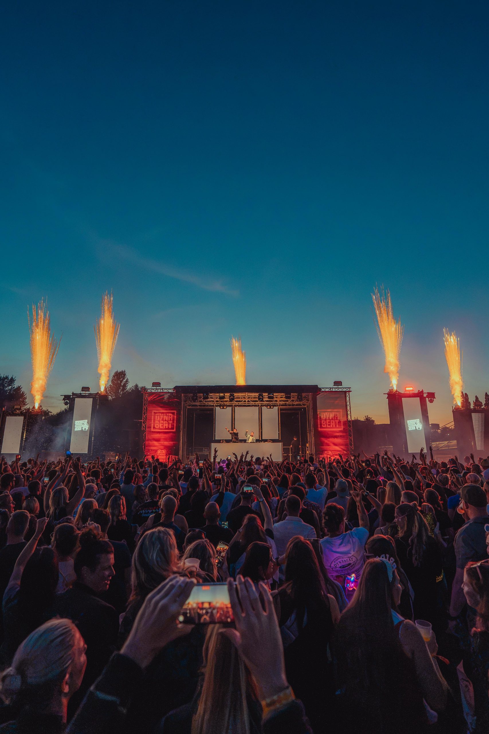 Publikum filmt die Pyro- und Lichtshow von CUE PAL beim DYNABEAT Festival in Geesthacht in der Daemmerung